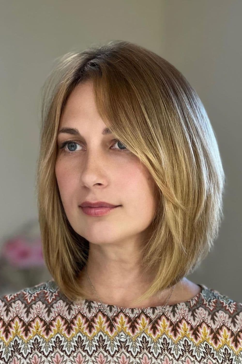 A woman with a blonde side-parted shoulder-length bob cut.