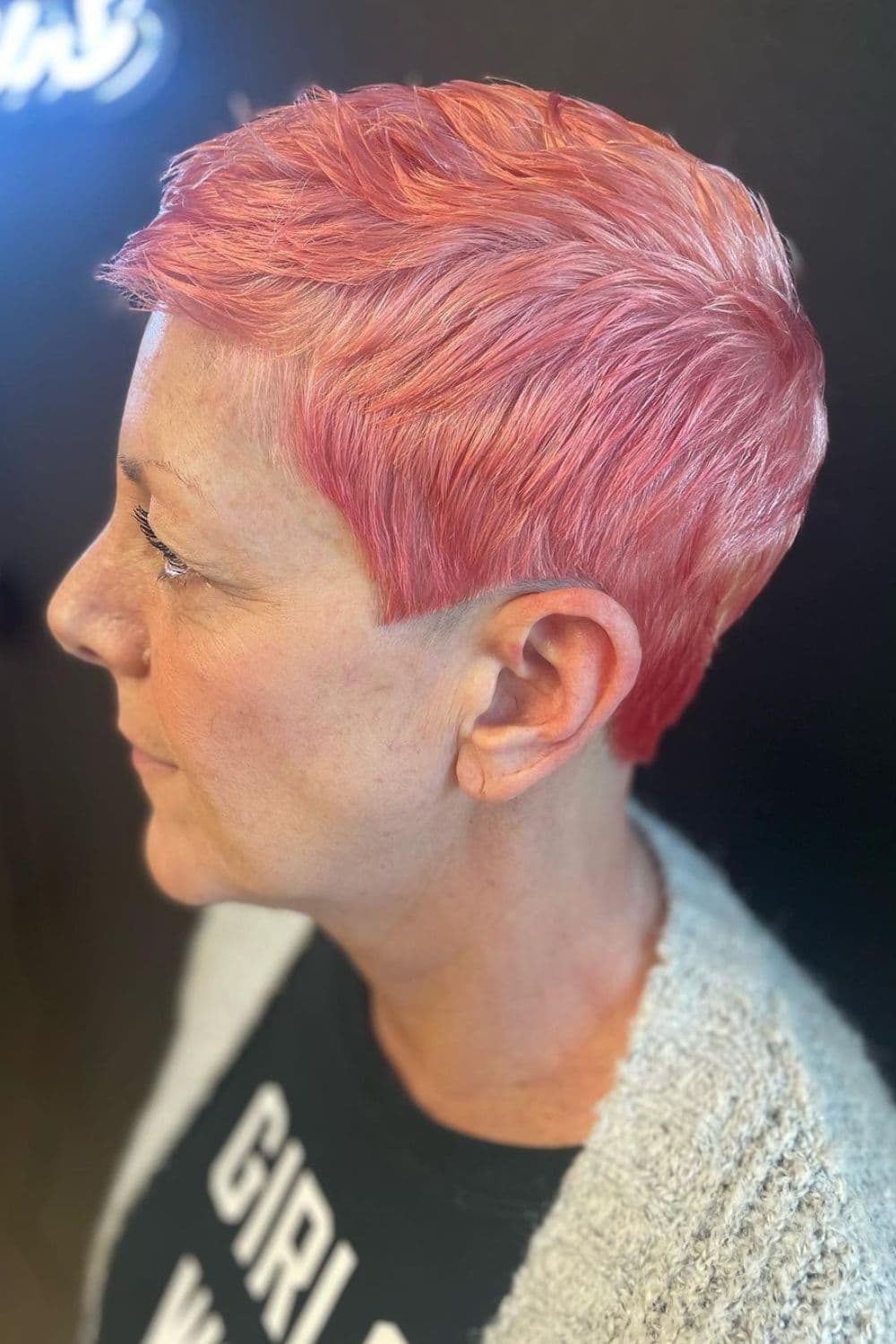 A woman with a pink side-parted textured pixie cut.