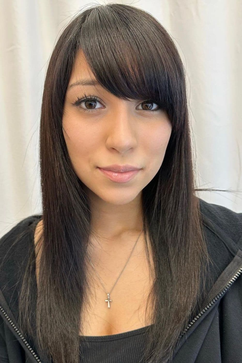 A woman with black medium-length hair with side-swept bangs.