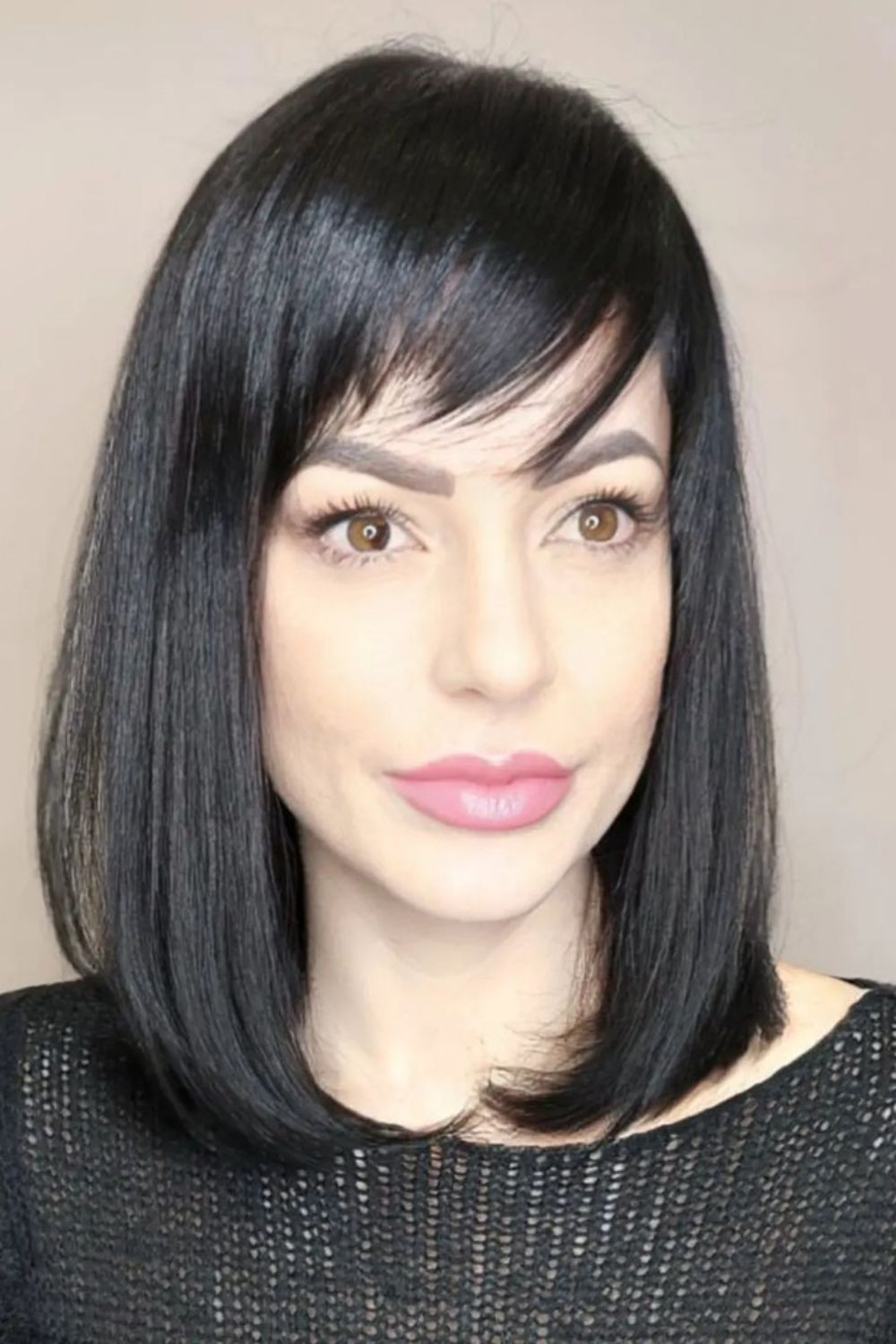 A woman with a black long bob cut and a side-swept layered bangs.