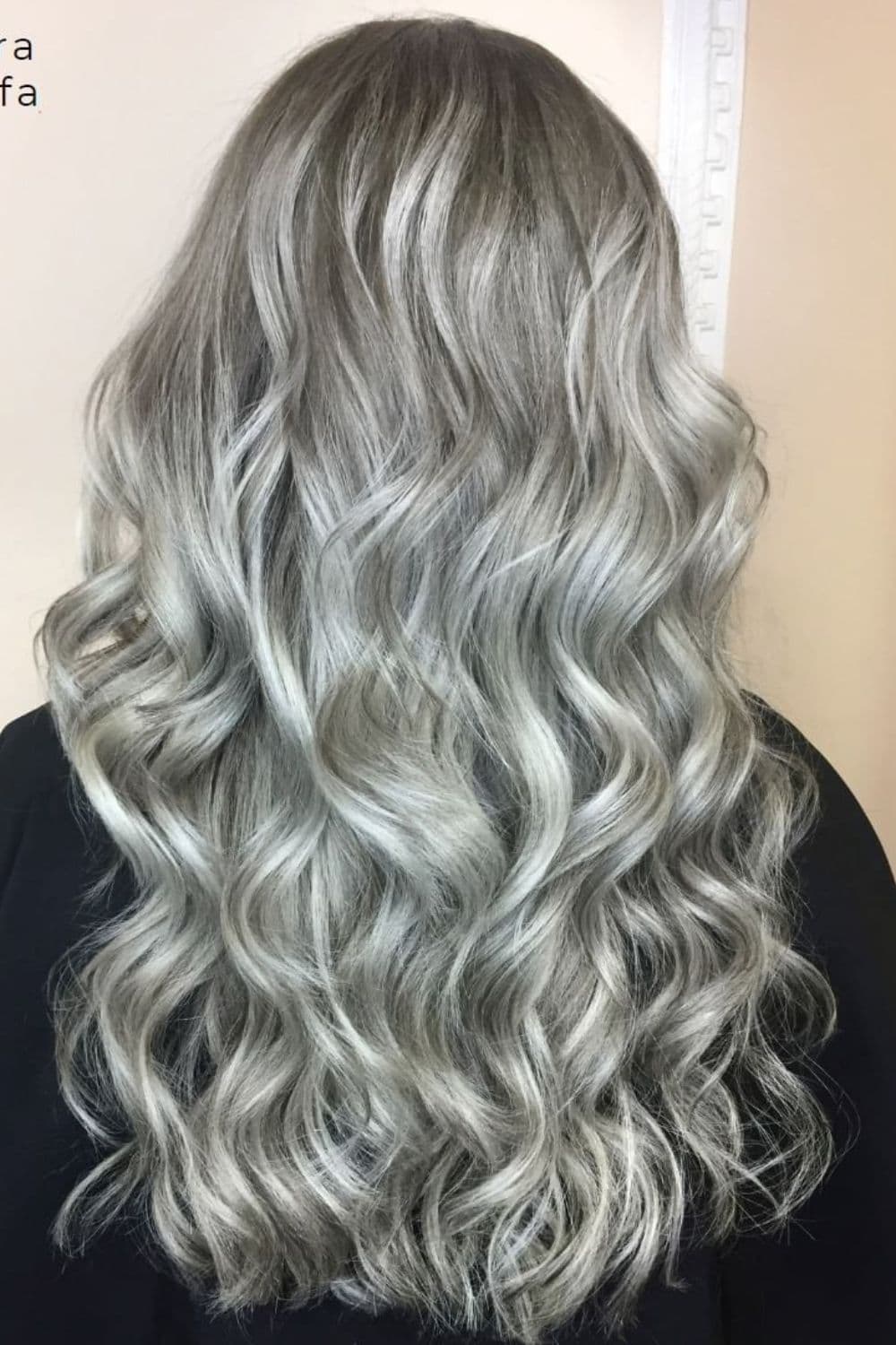 A woman with long silver dirty blonde hair with curls.