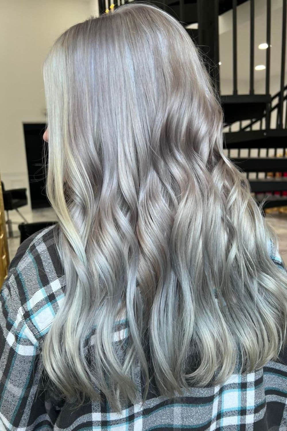 A woman with long wavy silver hair with white money pieces.