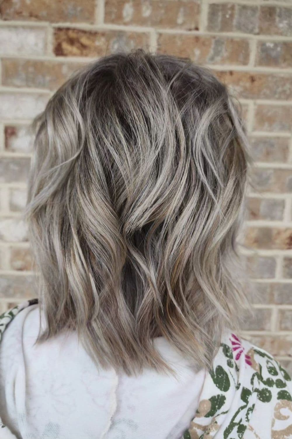A woman with lob silver highlights with shadow roots.