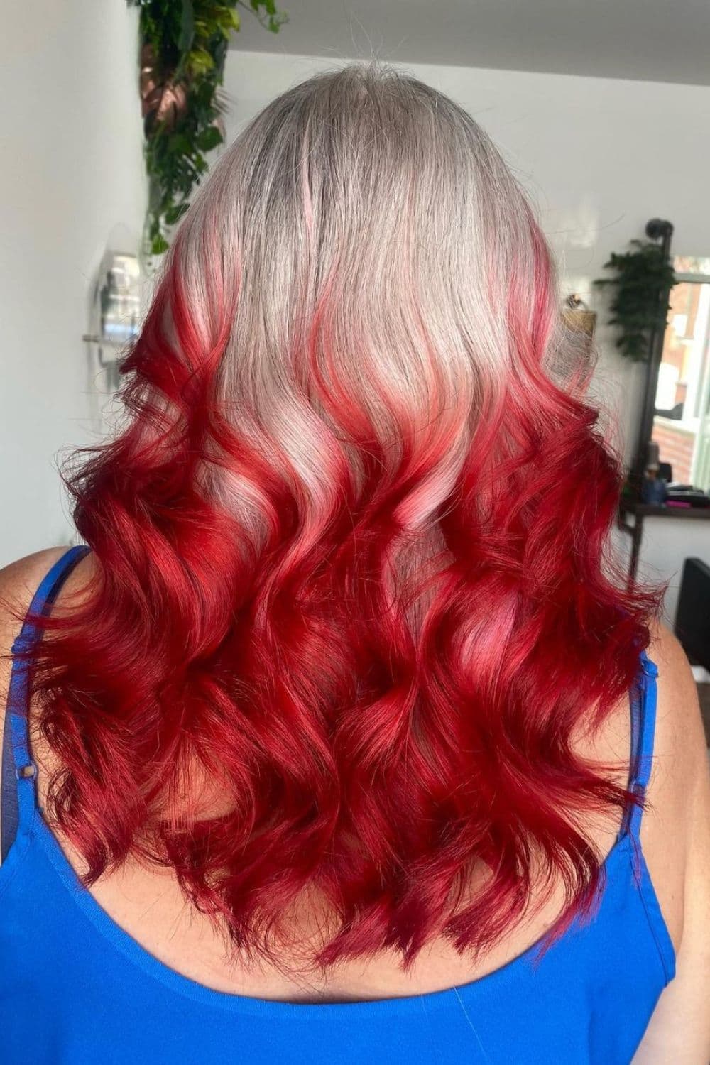 A woman with silver to red ombre hair with loose curls.