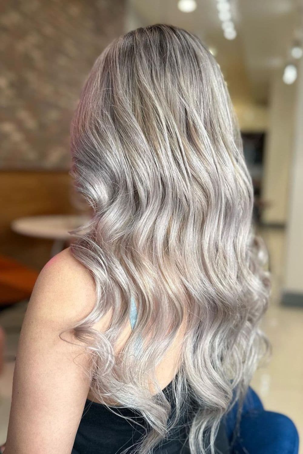 A woman with long silver and gray balayage.