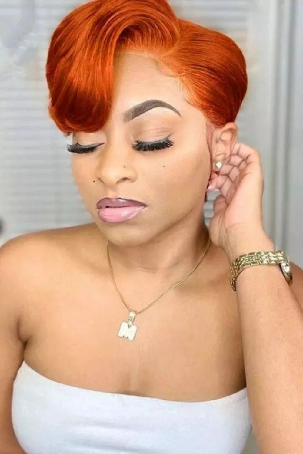 A woman with a straight ginger pixie with side bangs.