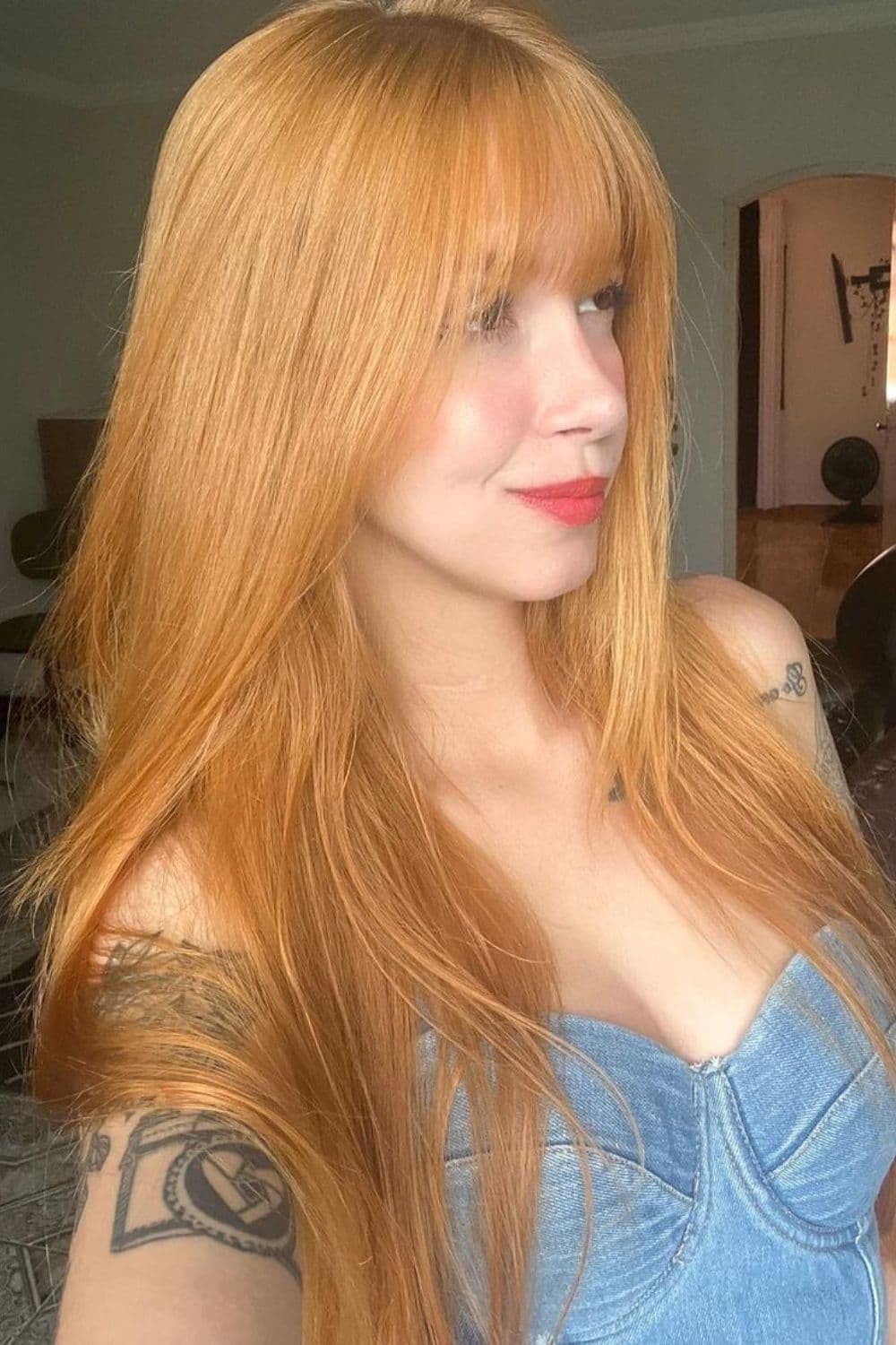 A woman with long strawberry blonde hair with bangs.