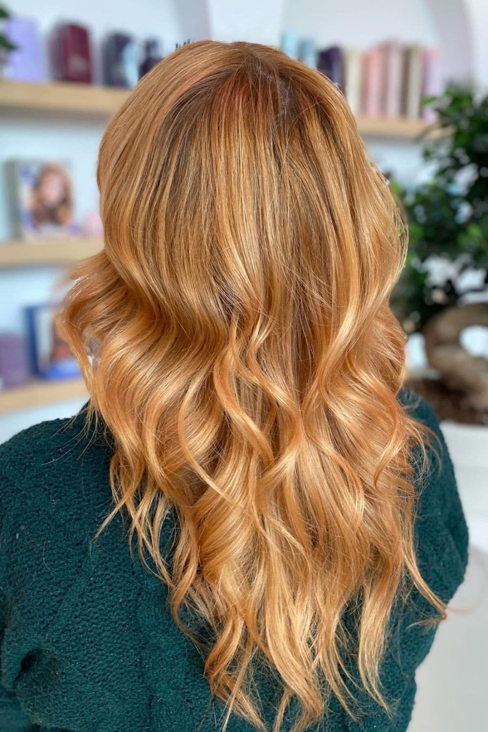 A woman with long strawberry blonde balayage with curls.