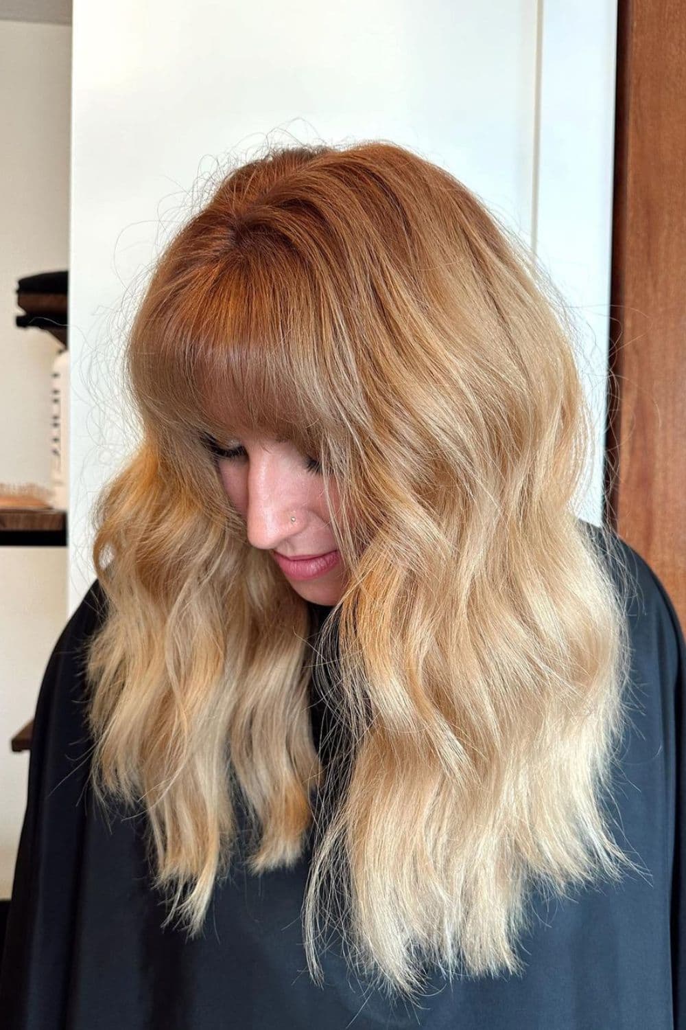 A woman with long strawberry blonde hair with classic bangs.