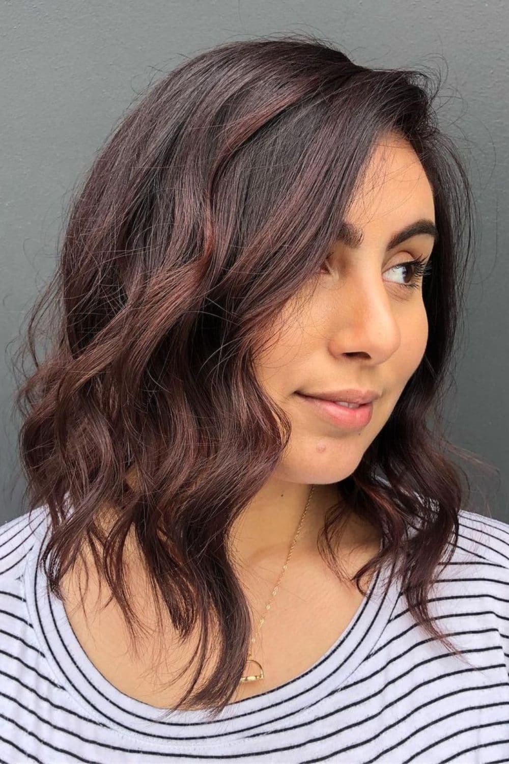 A woman with subtle dark brown ombre long bob with curls.