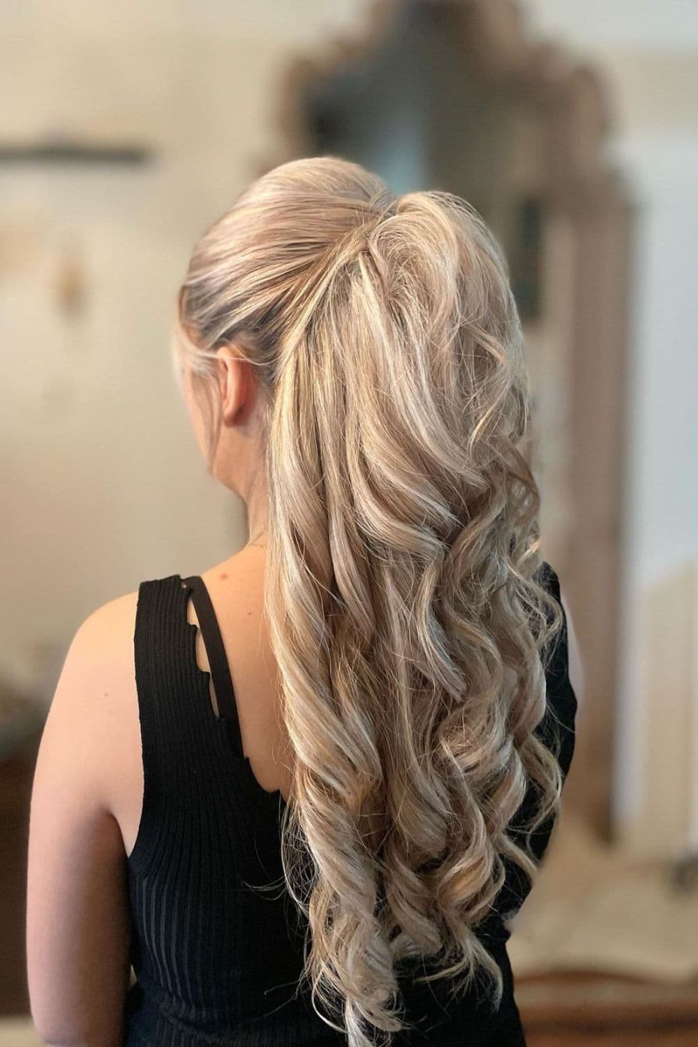 A woman with a blonde teased half-updo hairstyle.