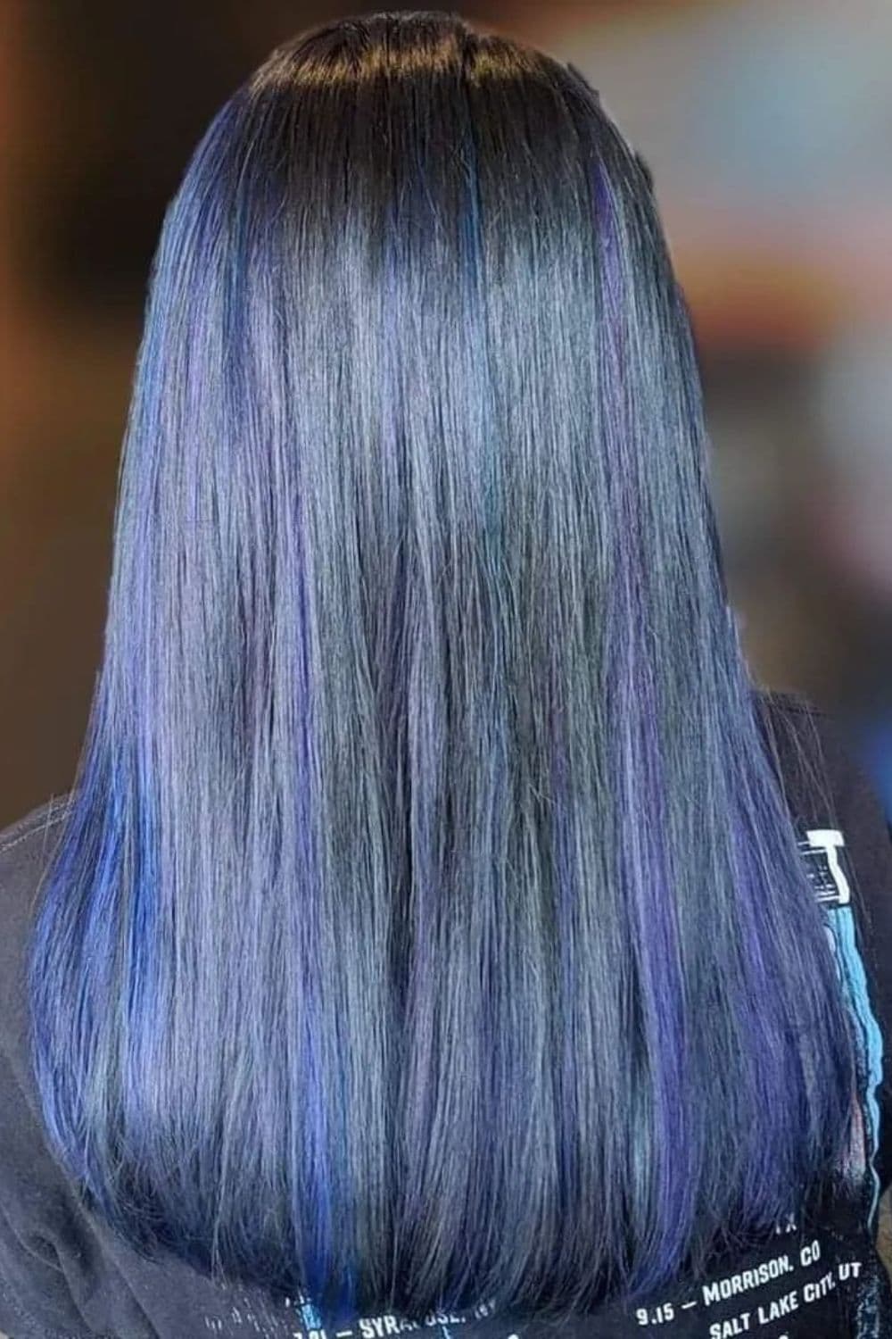 A woman with medium-length straight violet-toned blue black hair.