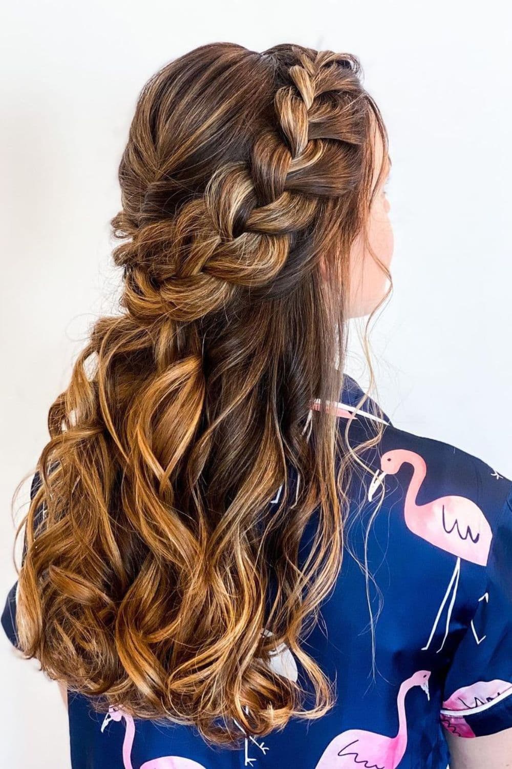 A woman with long brown hair with highlights and volumized French braid.