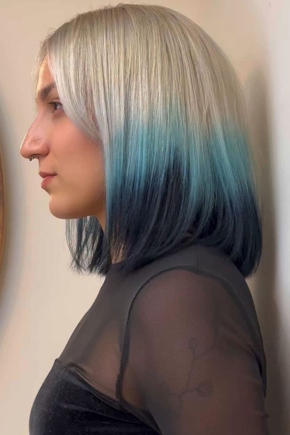 A woman with white blonde long bob with sky blue and glossy black dip-dyed ends.