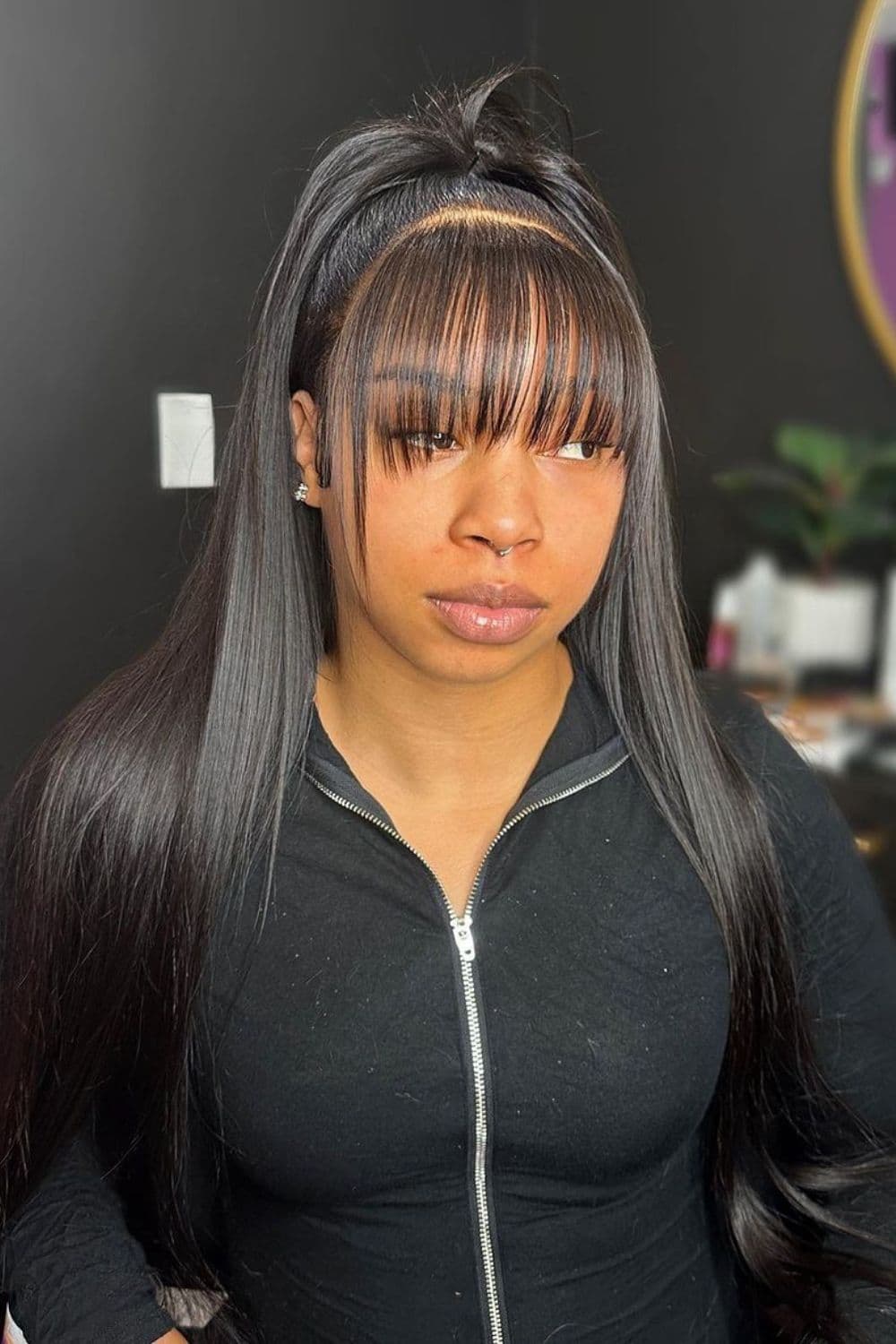 A woman with a straight, black wig hairstyle with bangs.