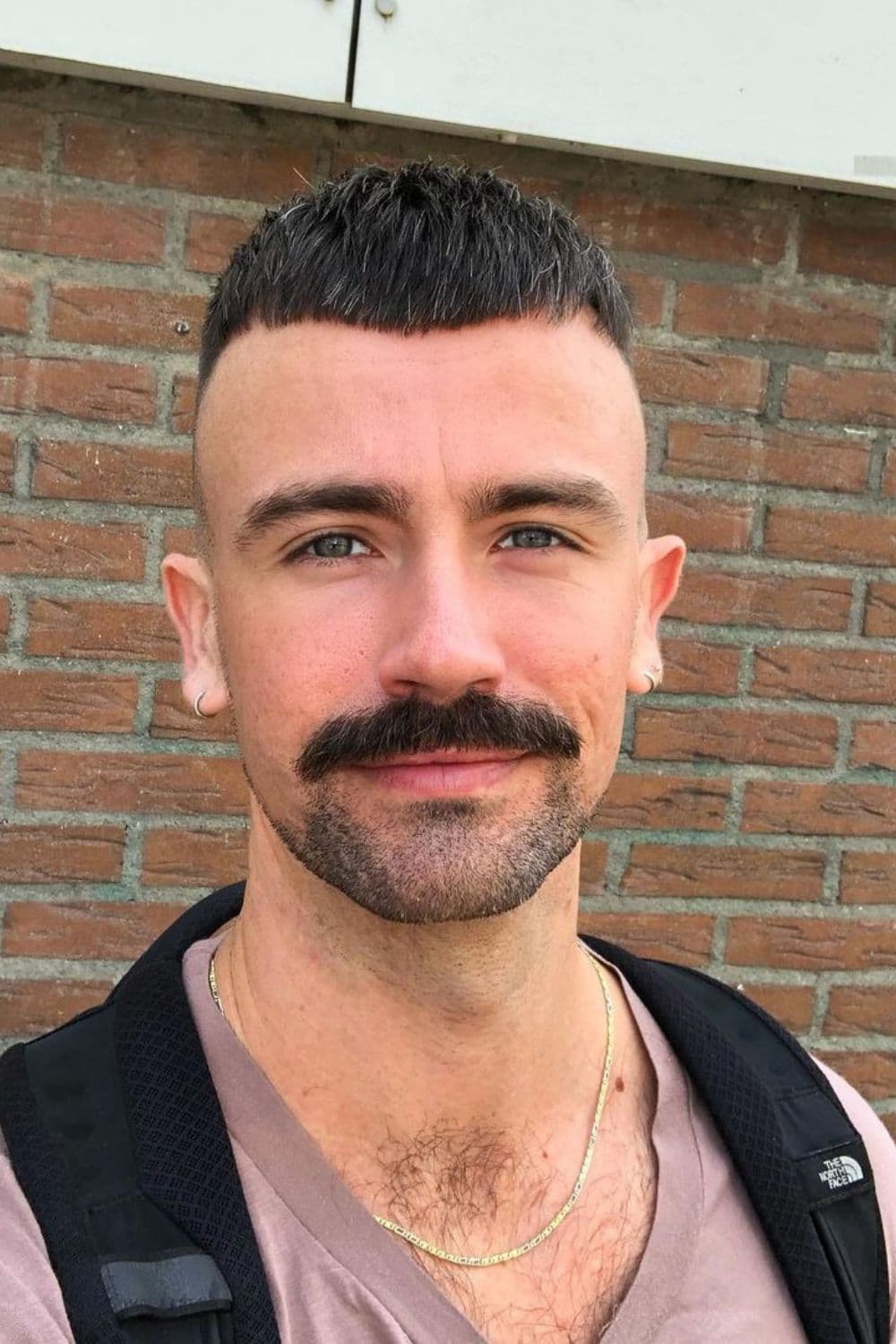 A man with a buzzed Caesar cut and a mustache.
