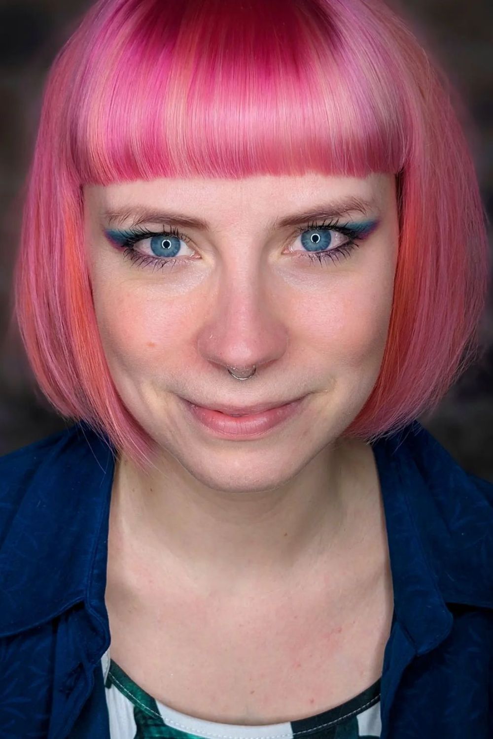 A woman with a pink chin-length bob with blunt bangs.