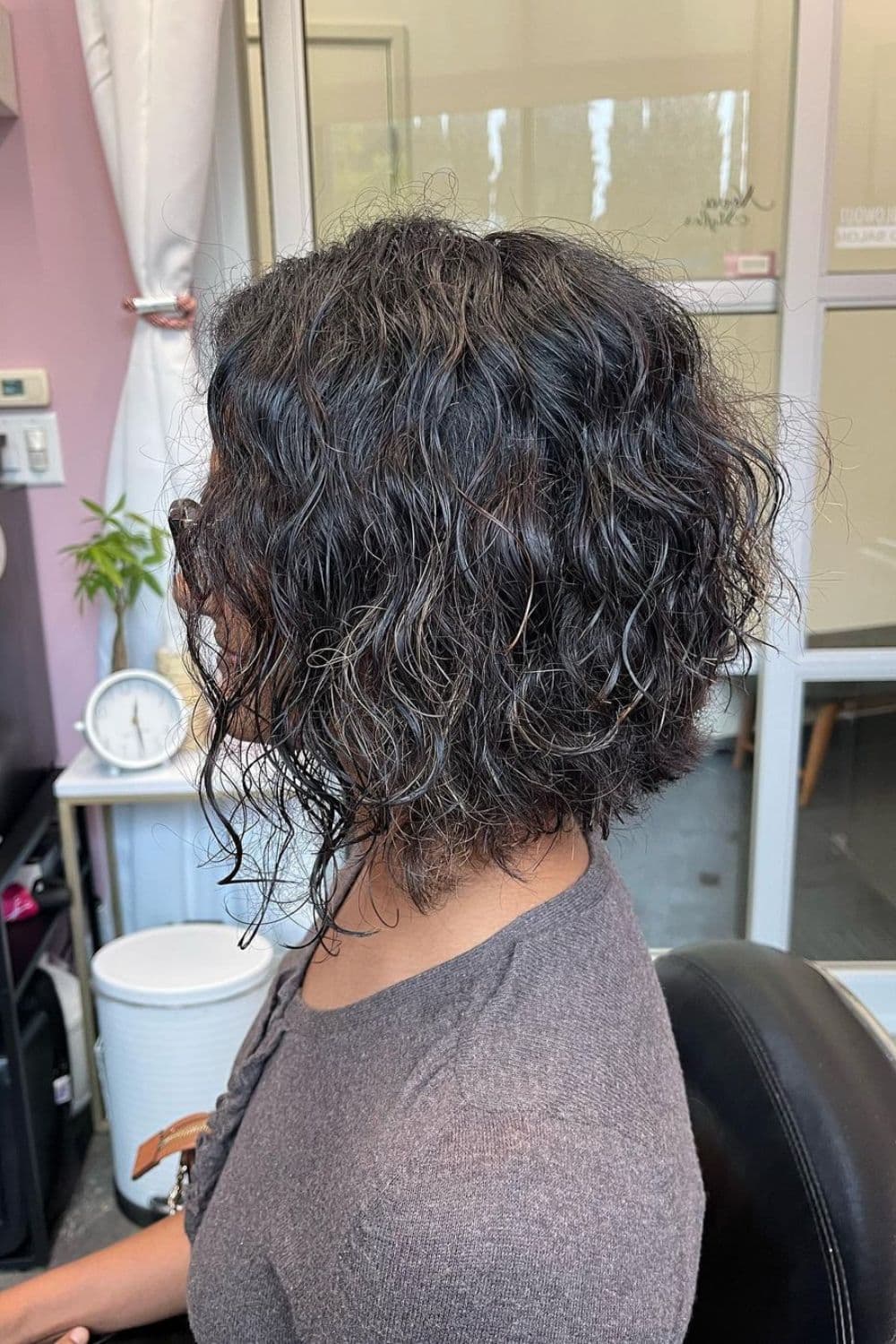 An old woman with a gray curly A-line cut with choppy layers.