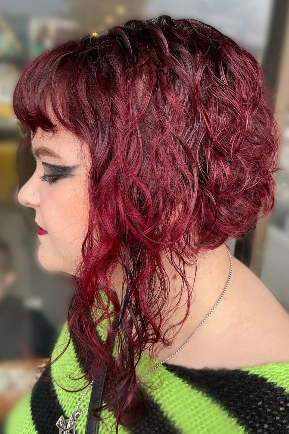 A woman with a red curly inverse bob with baby bangs.