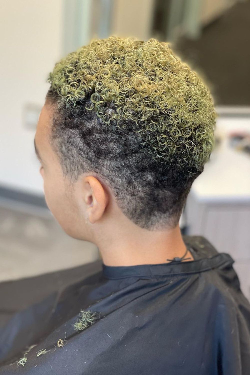 A woman with a black and blonde curly pixie with low taper side fade.