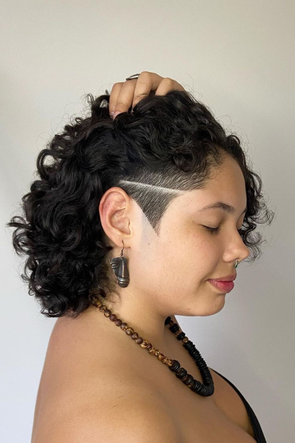 A woman with a black curly short sidecut.