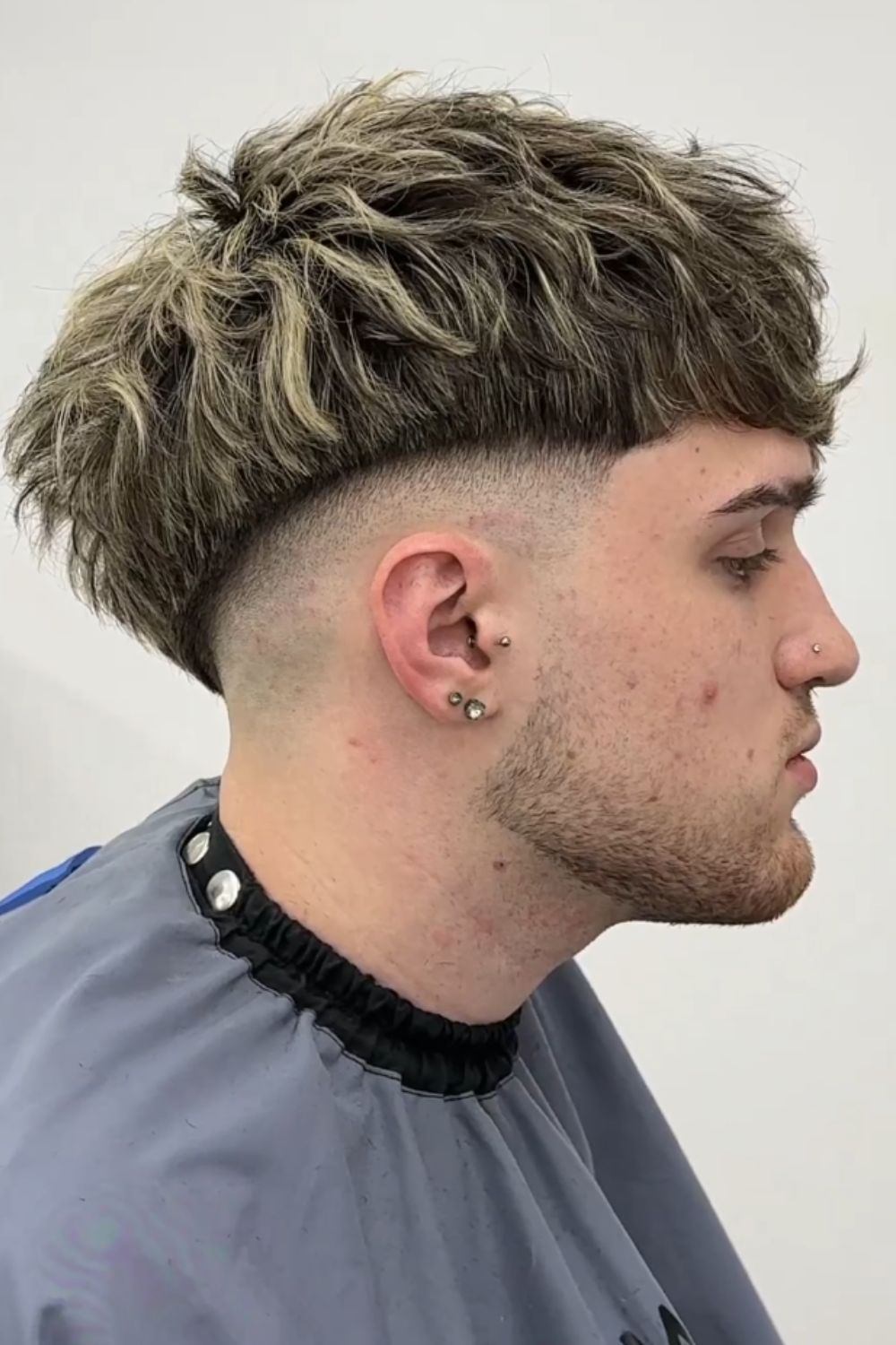 A man with a disconnected mid fade and highlights.