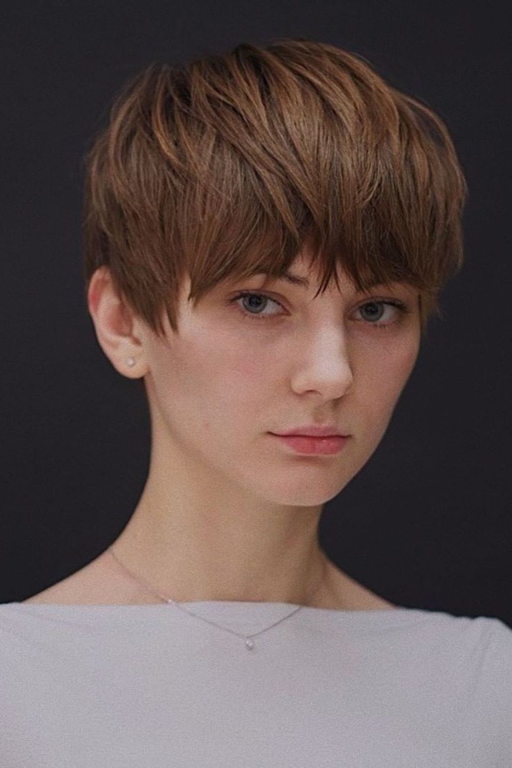 A woman with a brown layered pixie with full bangs.