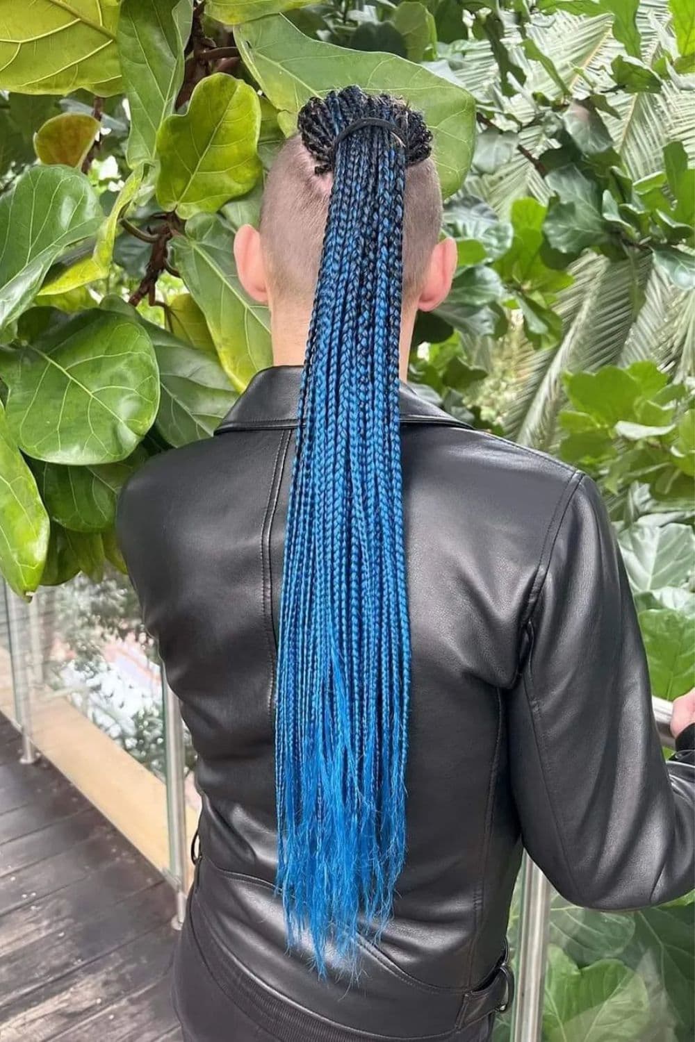 A man with a long blue box braids ponytail.