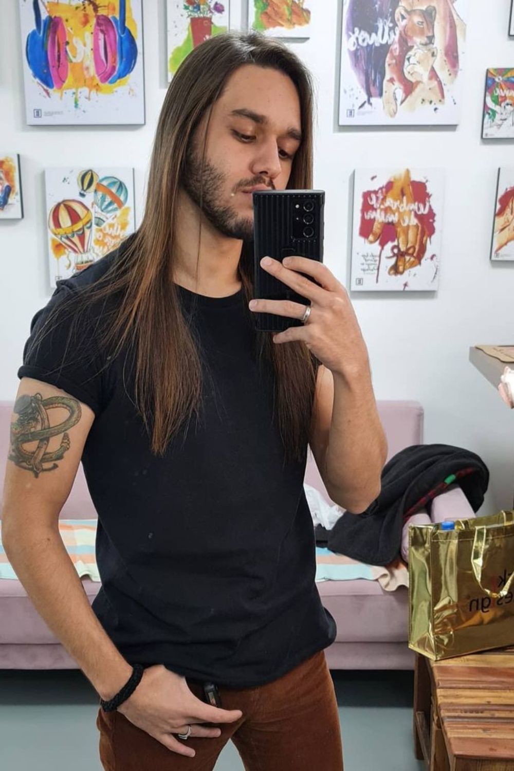 A man with a long straight hair is holding his phone.
