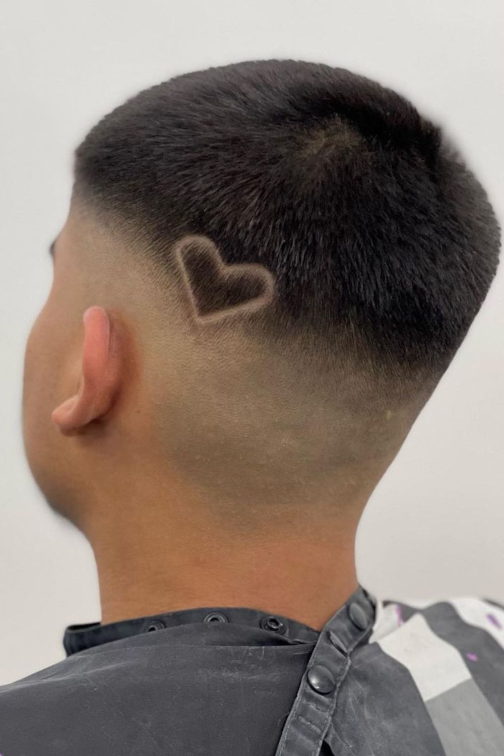 A man with a mid fade line up with a heart design.