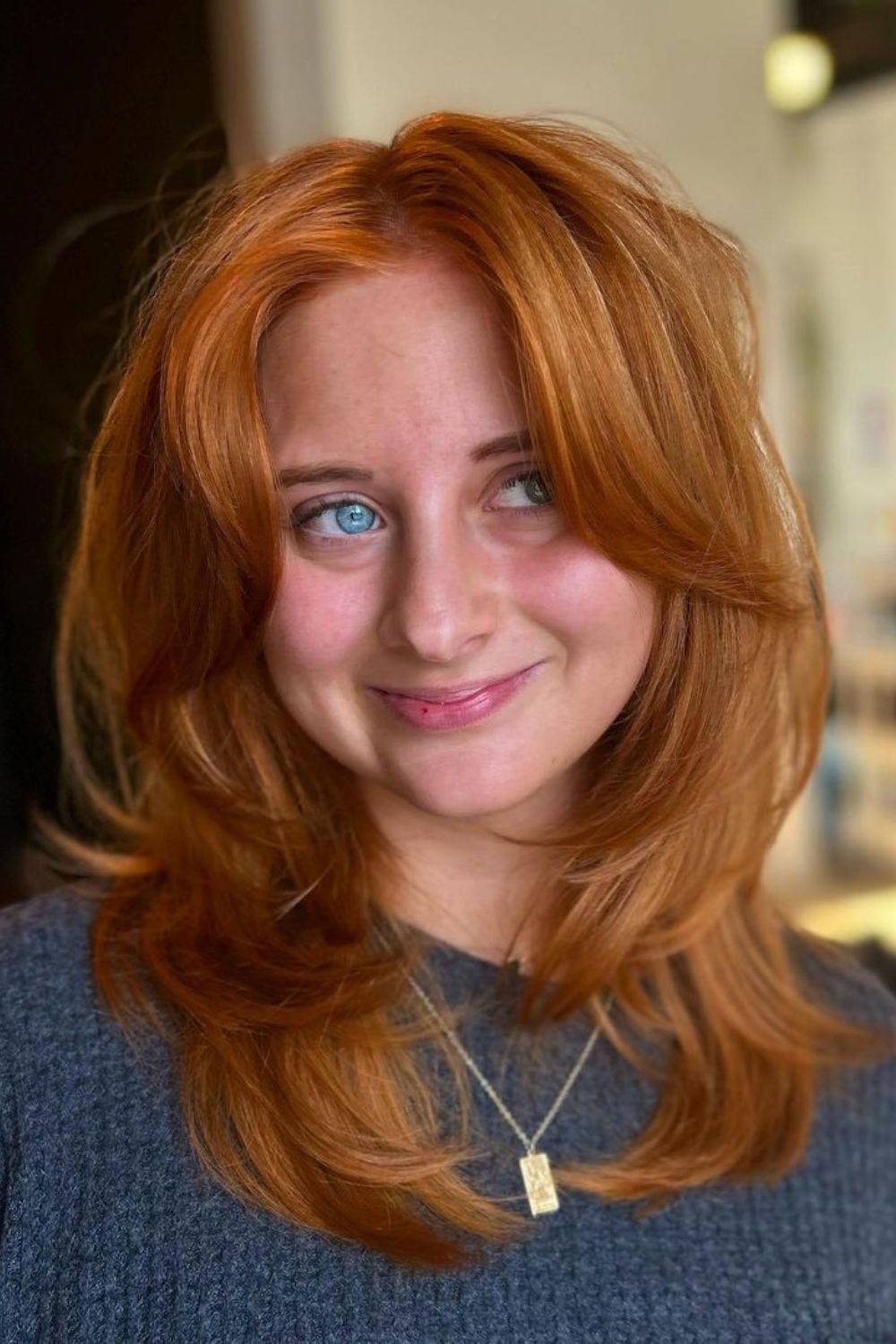A woman with mid-length ginger hair with curtain bangs.