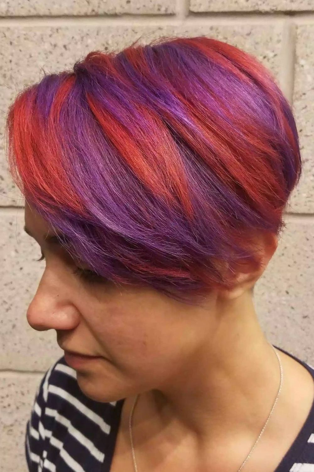 A woman with short hair with a purple and red hair color spray.