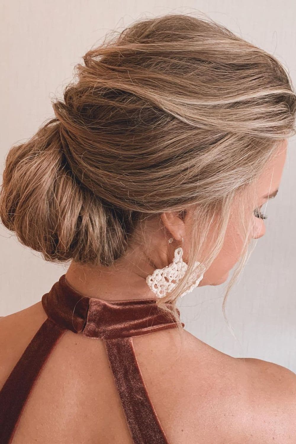 A woman with a blonde rolled low bun hairstyle.