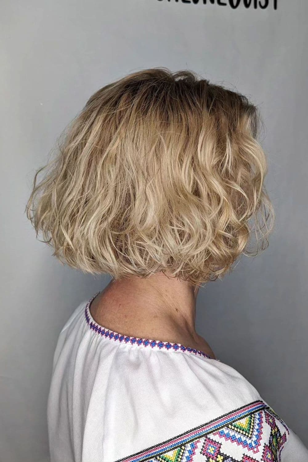 A woman with a short blonde feathered curly bob.
