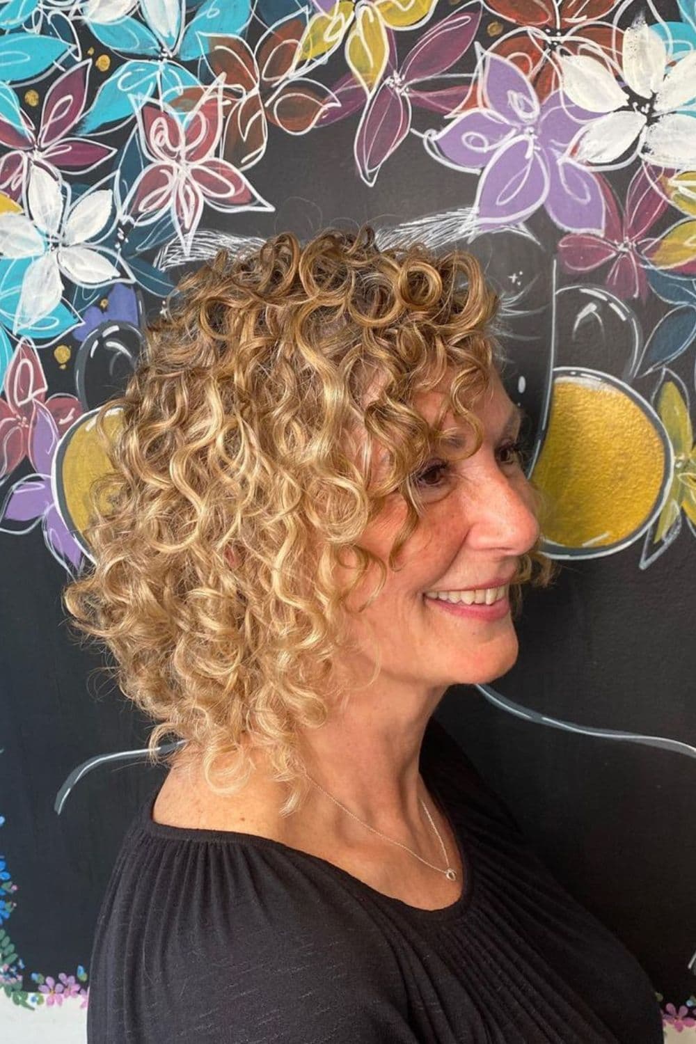 A woman with a shoulder-length blonde curly bob.