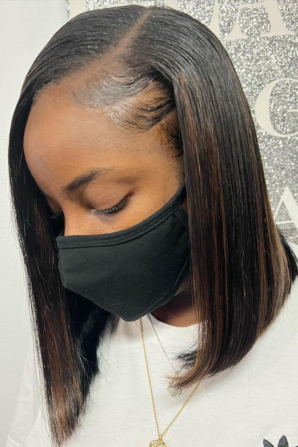 A black woman wearing a black mask with a side-parted angled bob cut.
