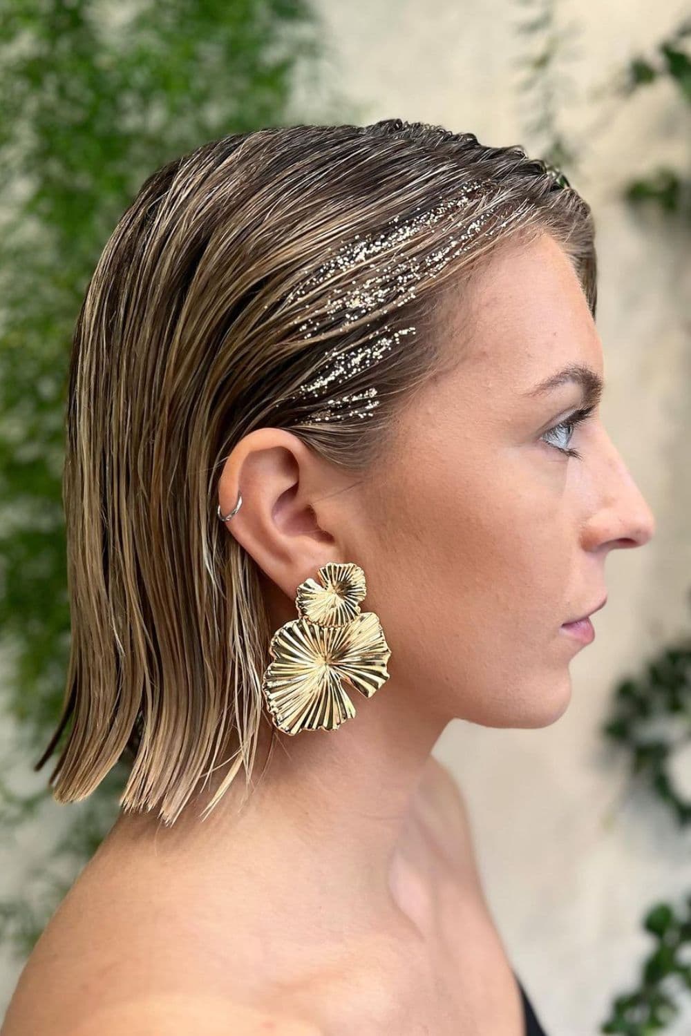 A woman with a short blonde slicked-back wet look with a touch of sparkle.