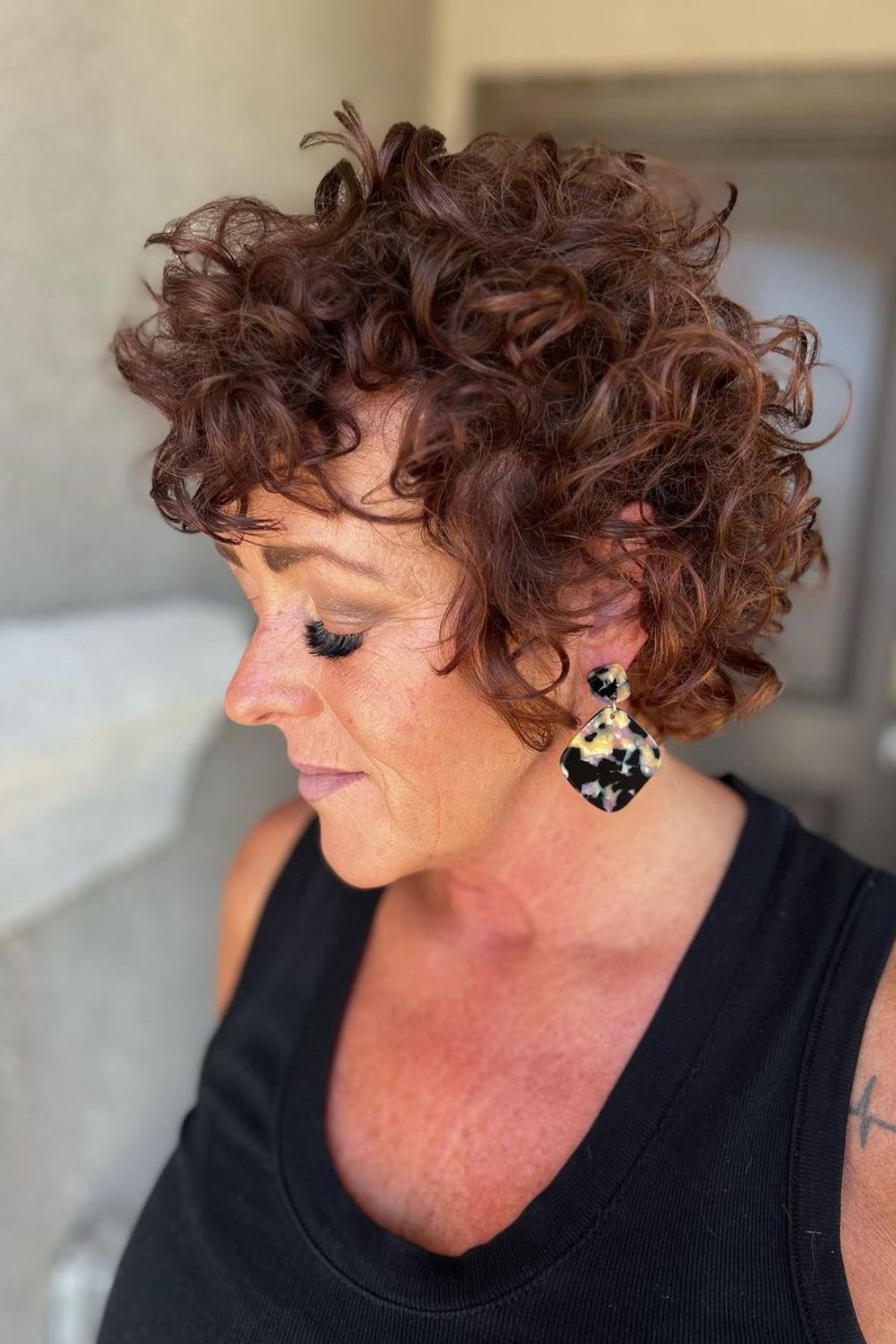 A woman with a brown tapered curly bixie.