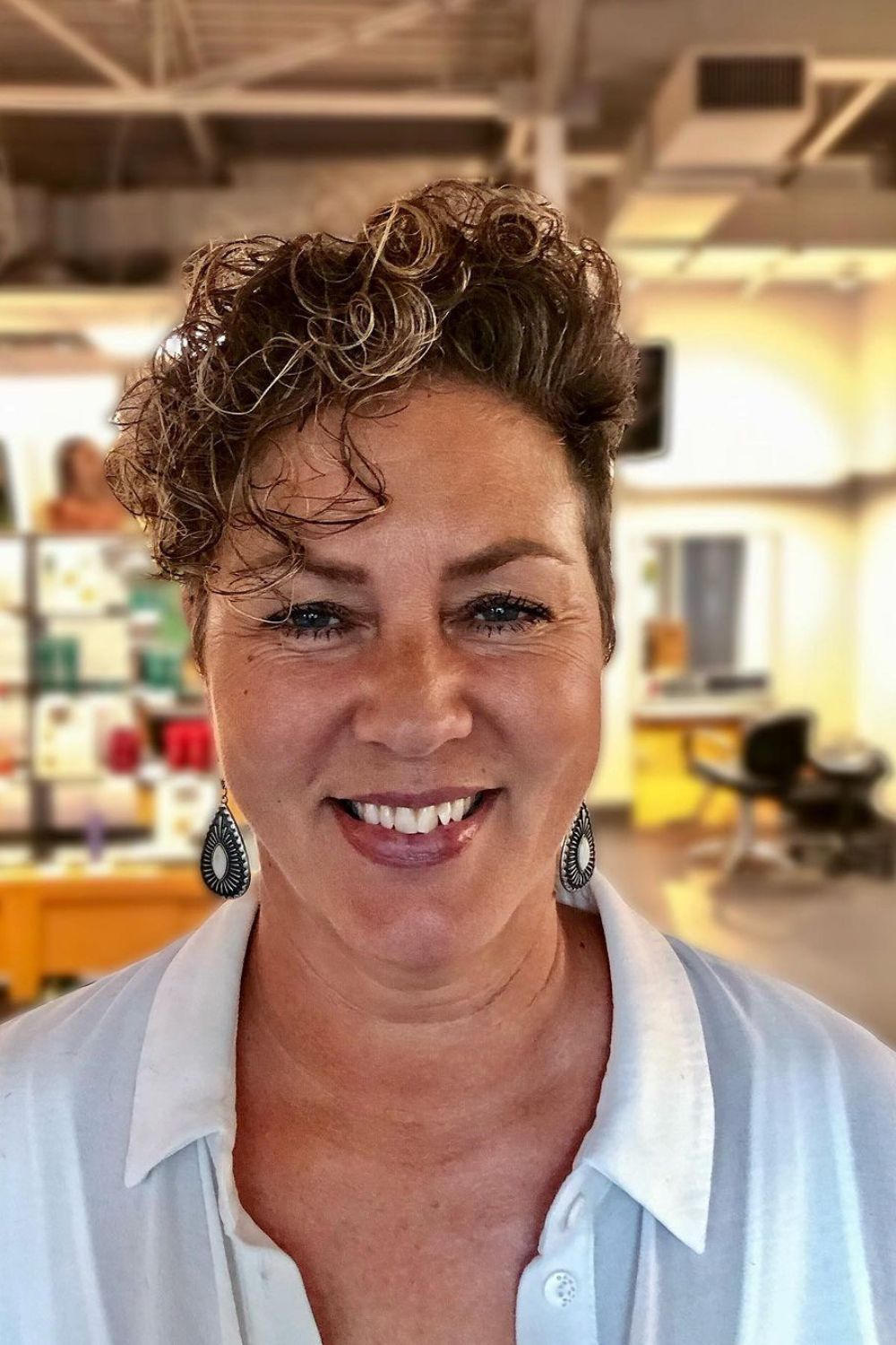 A woman with a tapered curly pixie with long side bangs.