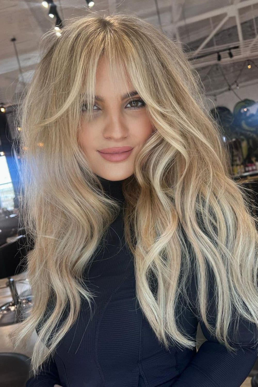 A woman with long blonde hair with wispy curtain bangs.