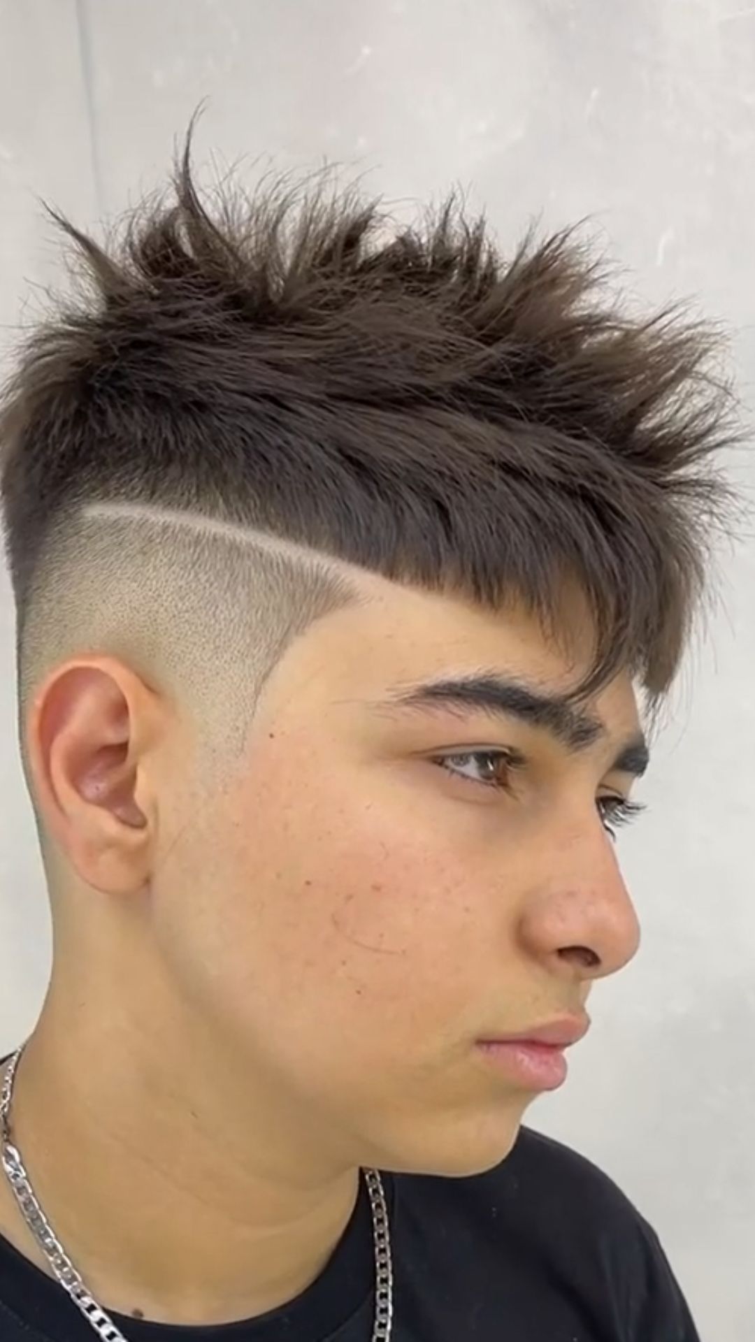 A teenage boy with a crop haircut with a hard part.