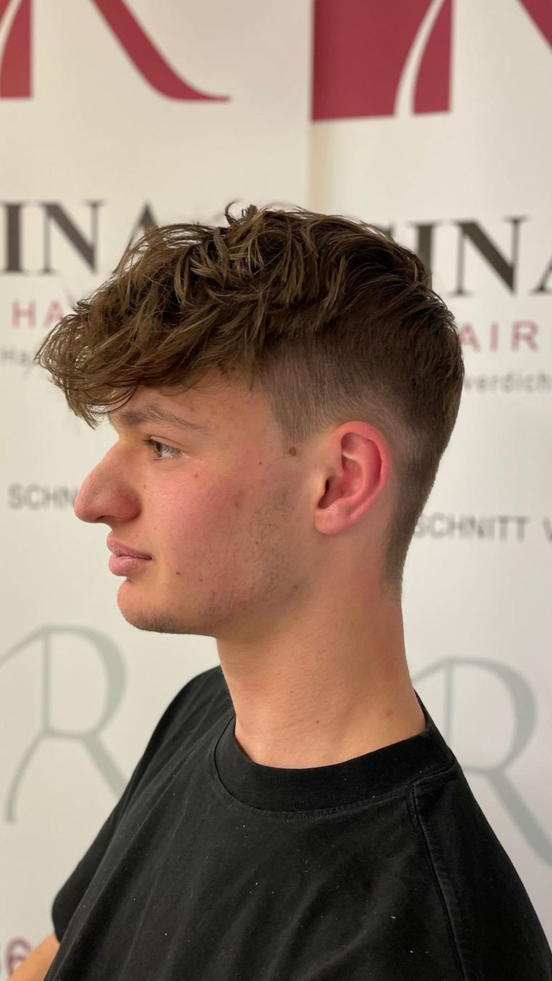 A man with a long textured fringe and mid fade.