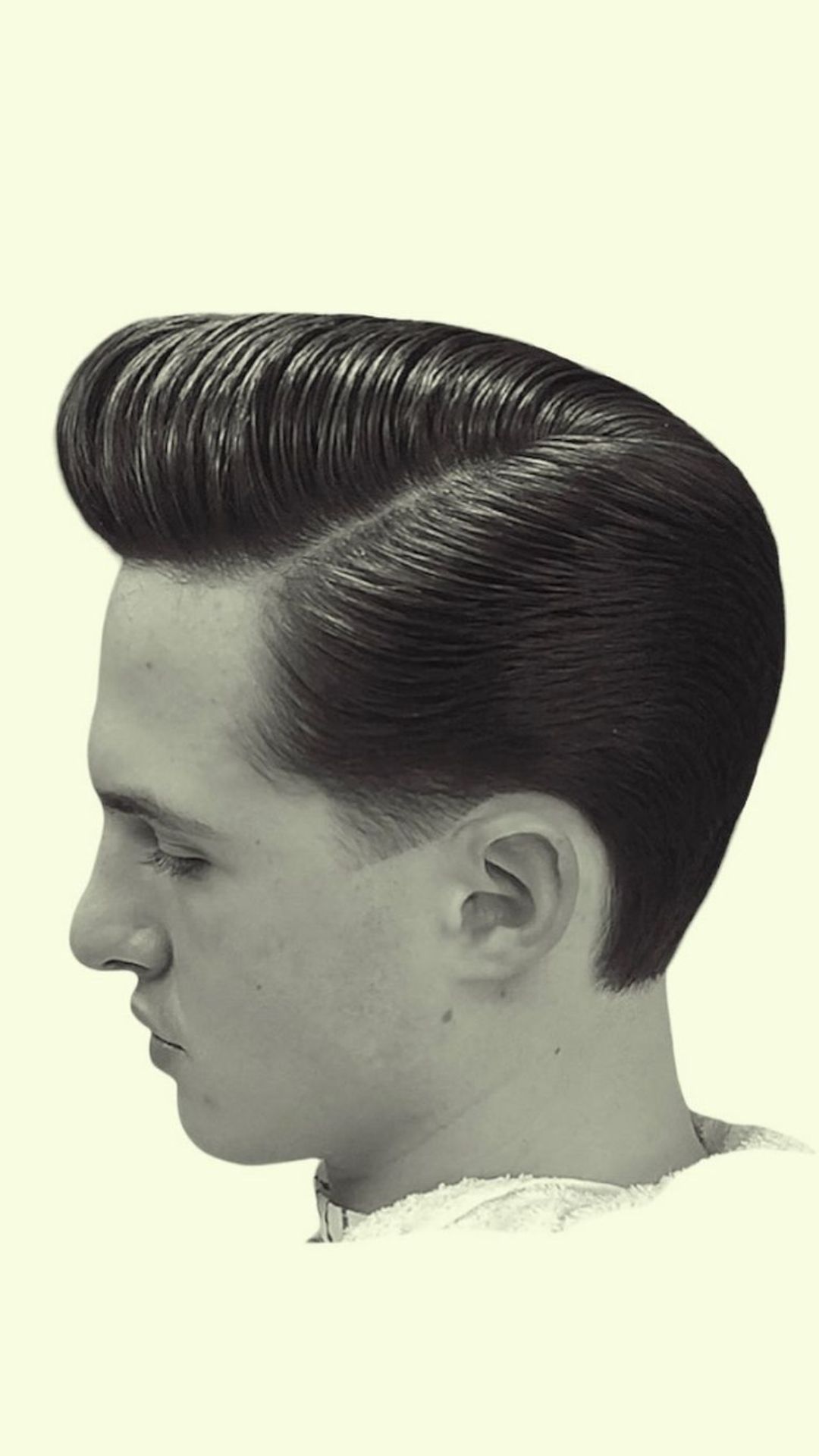 A man with a low skin fade and a hard sideswept pompadour.