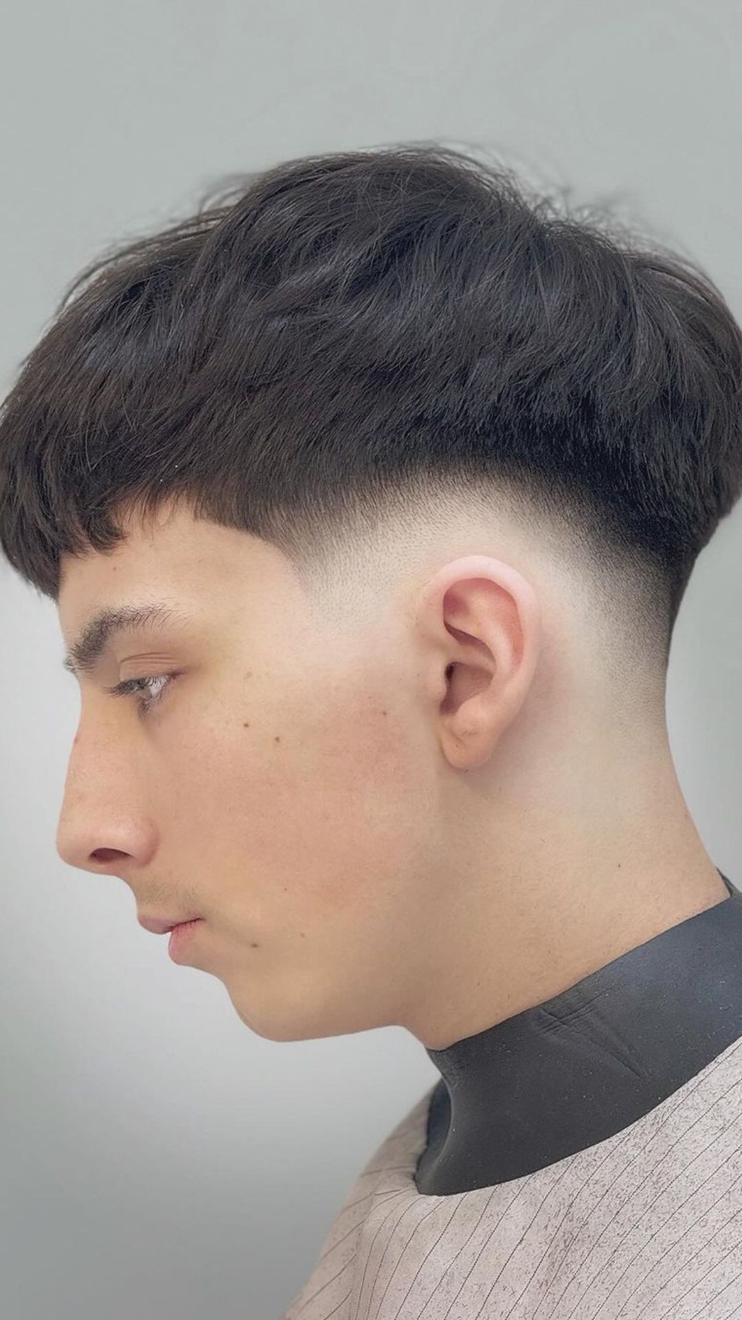 A man with a low skin fade and textured crop haircut.