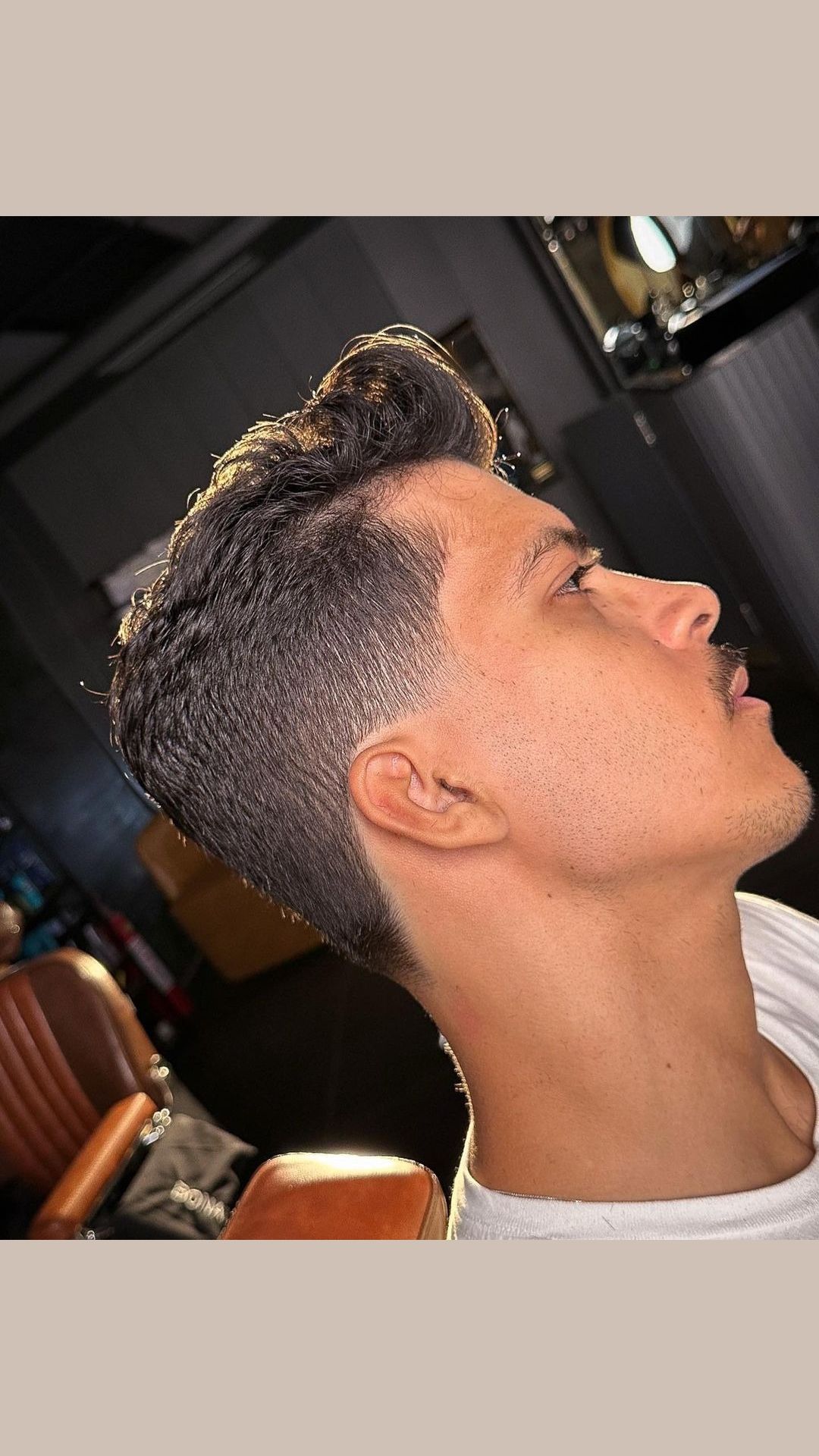 A man with a low taper fade and brushed up hair.
