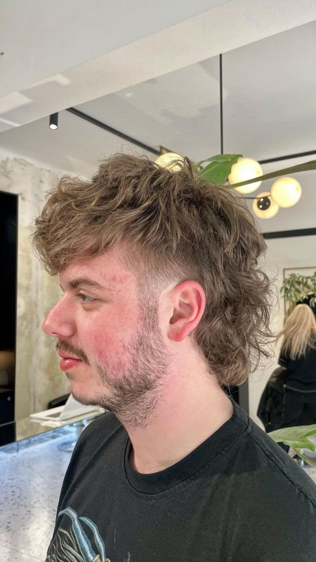 A man with a messy mullet hairstyle.