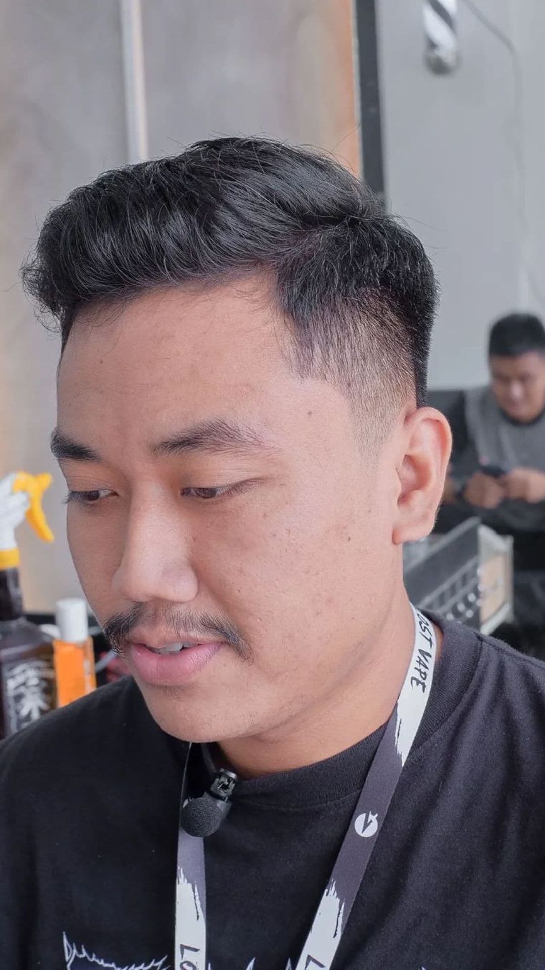 A man with a short pomp and low fade haircut.