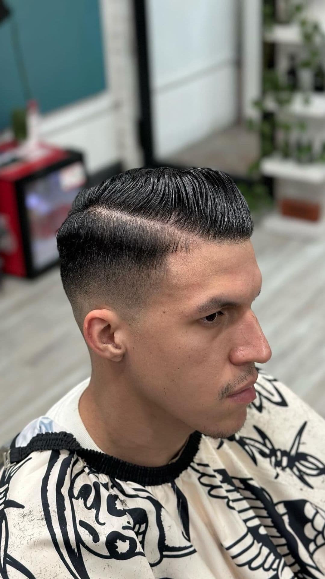 A man with a short side part and a fade haircut.