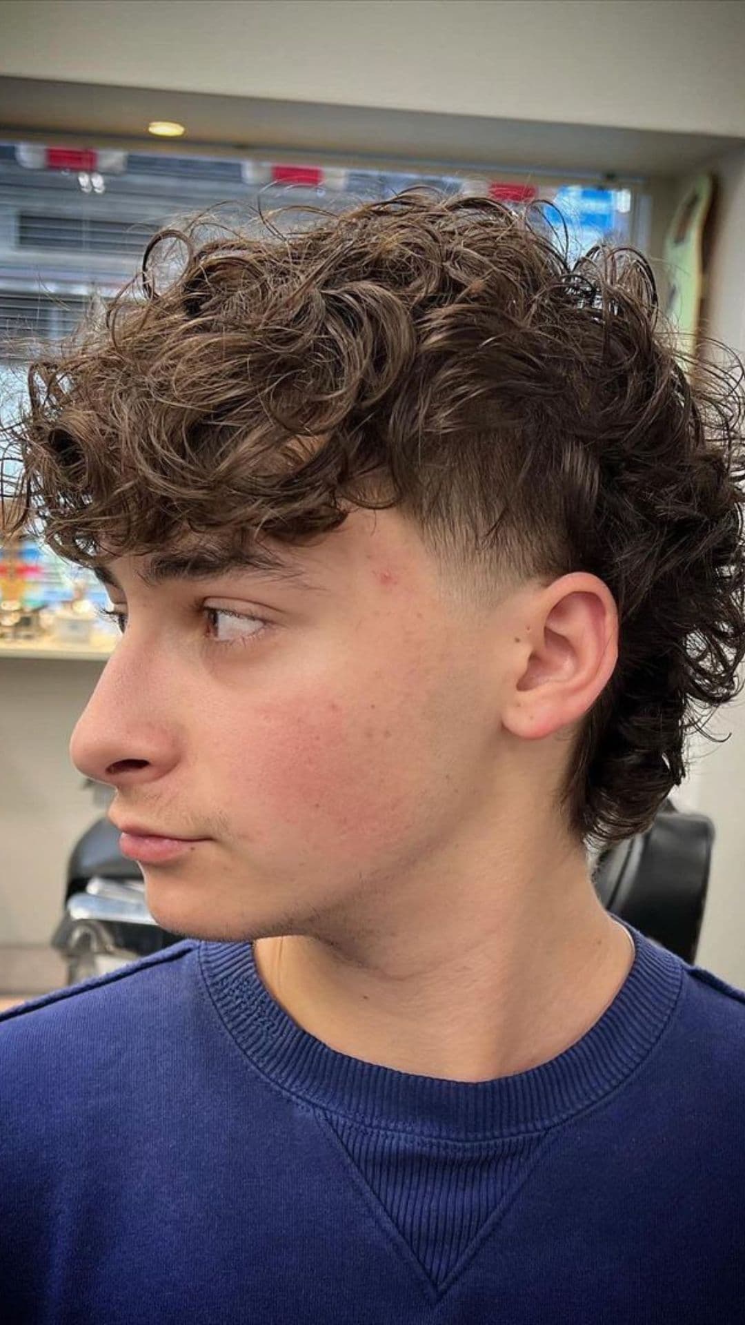 A man with a curly hair and taper fade mullet.