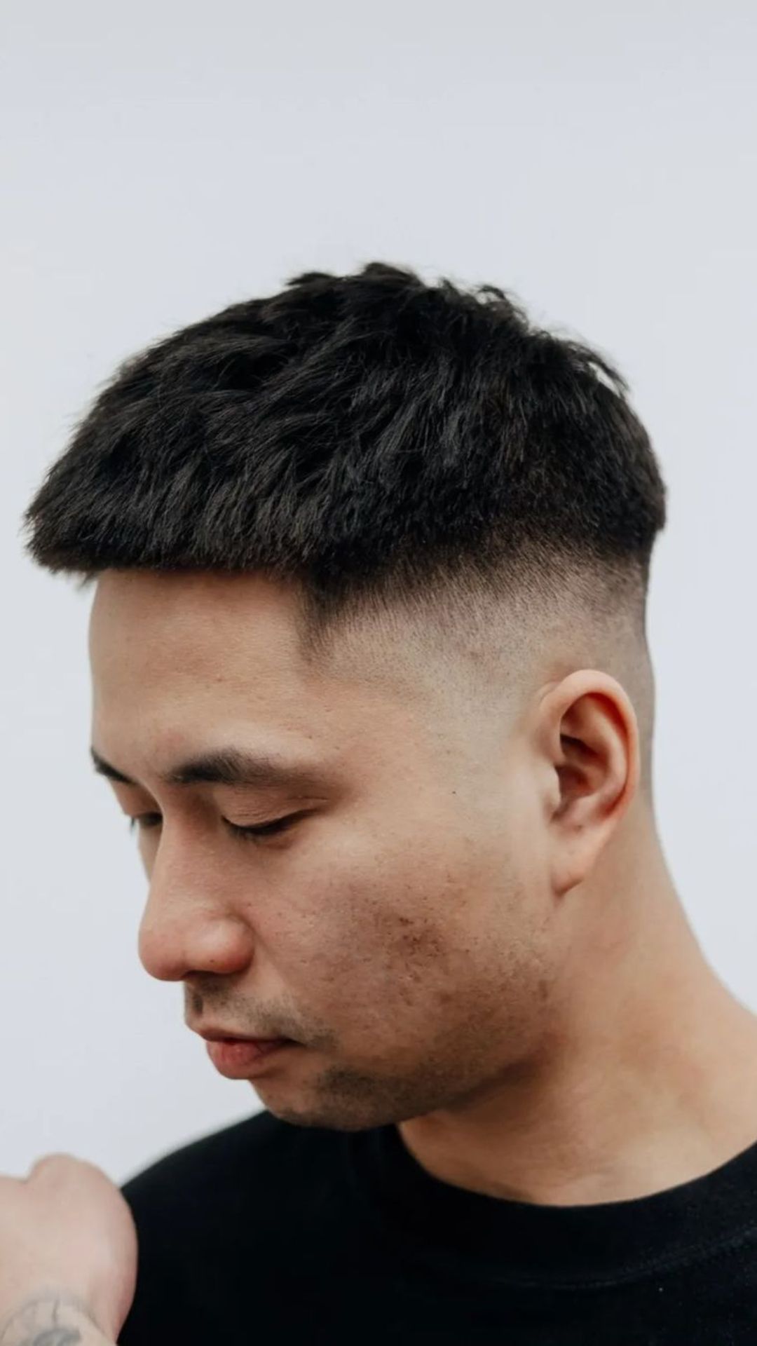 A man with a textured crop and high fade haircut.